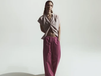 Model Anouk Smits posing in a striped short-sleeve shirt and magenta wide-leg trousers against a white seamless background.