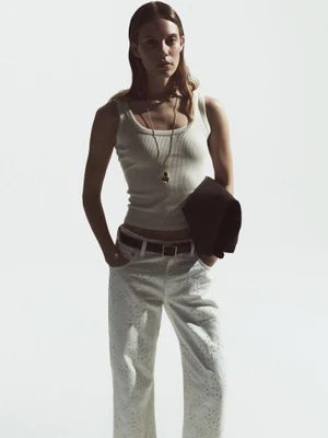 Model Anouk Smits wearing a white ribbed tank top and white eyelet pants against a white background for Citizens of Humanity.