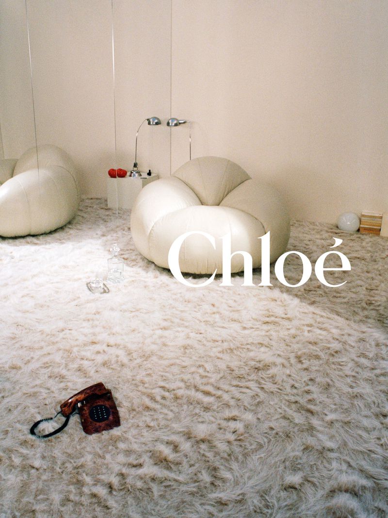 Interior with white cloud-shaped chair, fluffy rug, and telephone. Beige walls and ample light create a serene atmosphere.