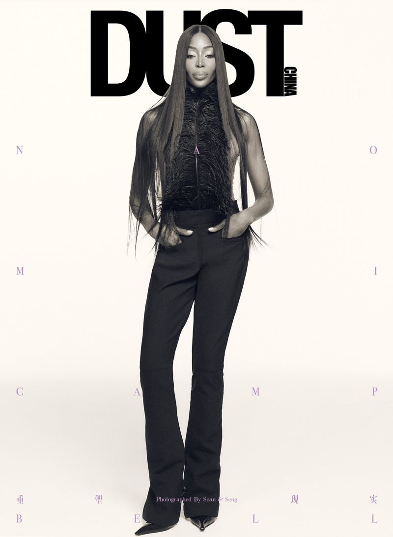 Magazine cover featuring a full-length shot of a fashion model in black pants and a feather top against a neutral gradient background.
