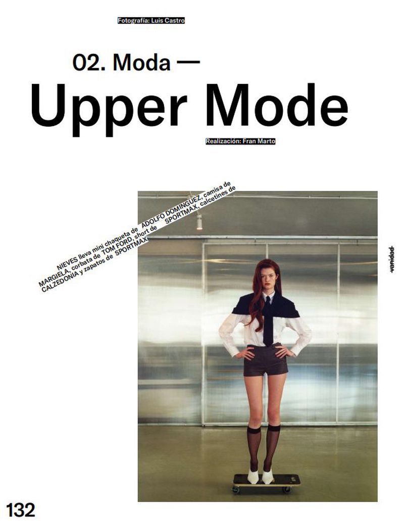 Editorial fashion shot of a young adult woman in black-and-white top, shorts, and patterned tights posing on a skateboard against a silver wall.