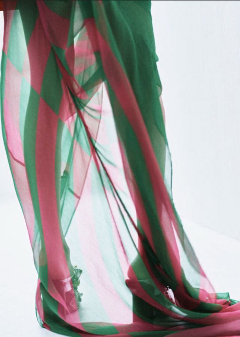 Sheer striped fabric in pink and green, cascading down and lit by studio lighting against a clean, minimalist white background.