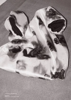 Draped silk garment with an abstract smoky black and white print laid on a neutral flat surface.