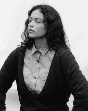 Monochrome portrait of model Devyn Garcia wearing a button-up shirt and dark knit cardigan against a pale studio backdrop.