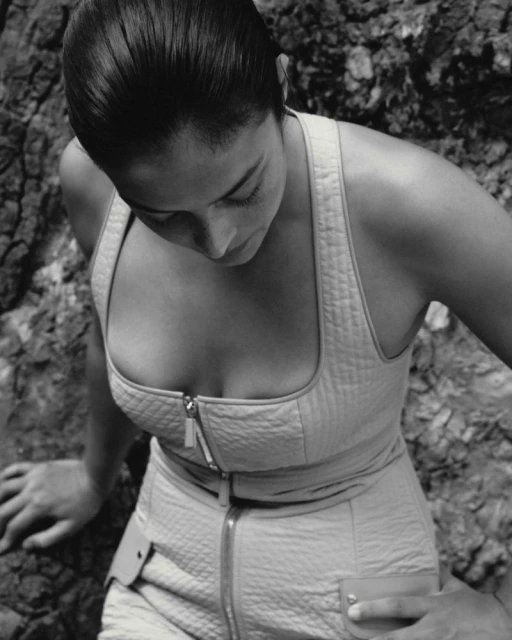 Adult female model poses in neutral-colored, zippered, quilted sleeveless jumpsuit in front of rock formation for a fashion editorial.