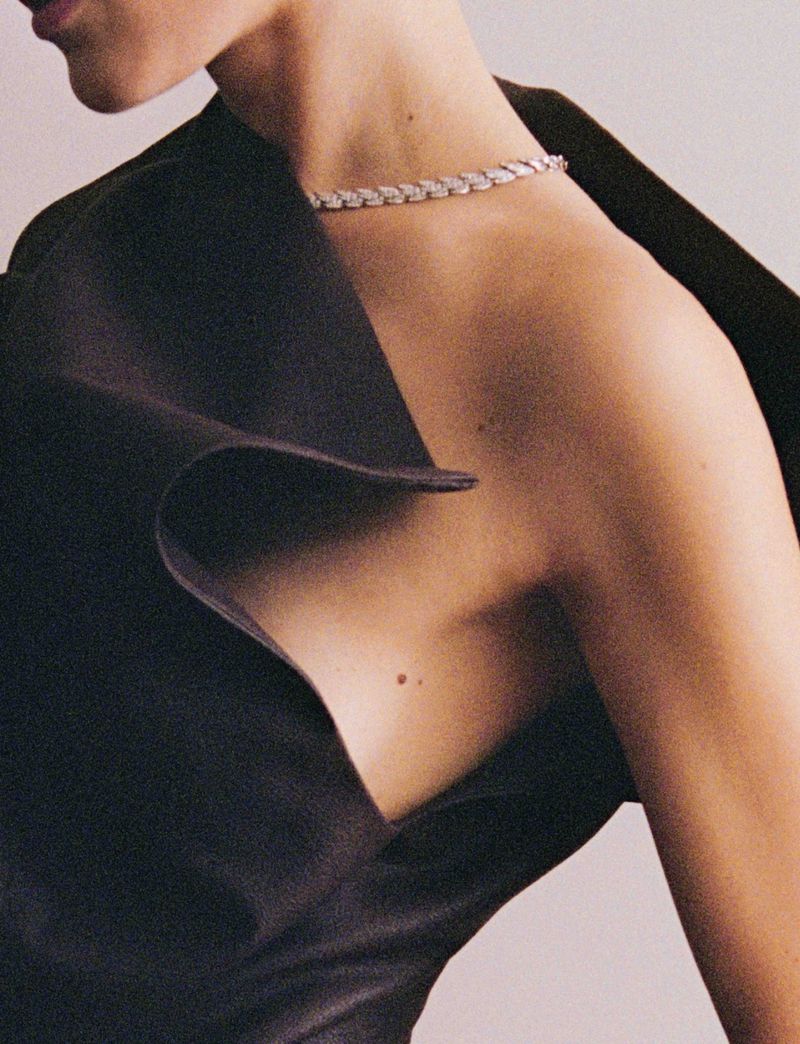 Elegant close-up of a woman with fair skin wearing a sleek black top and a delicate diamond necklace, showcasing fashion and beauty.