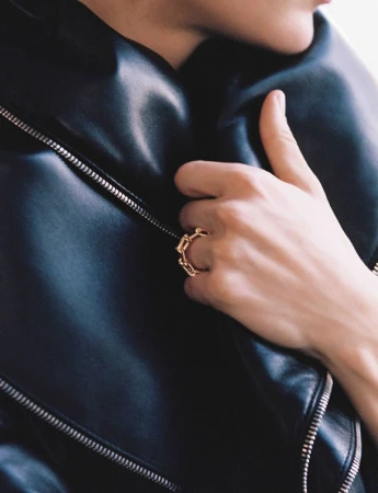 A close-up shot features a person wearing a black leather jacket and a distinctive gold ring, creating a chic and stylish aesthetic.