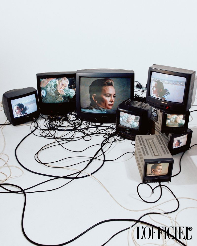 Collection of vintage televisions displaying portraits and nature scenes against a bright white backdrop, with tangled black cords.