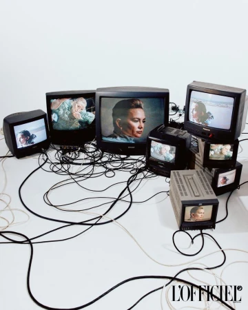Collection of vintage televisions displaying portraits and nature scenes against a bright white backdrop, with tangled black cords.