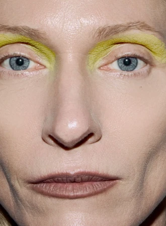 Extreme close-up studio portrait of an adult woman with blue eyes and yellow makeup on her eyebrows. Beauty shot for fashion and cosmetics.
