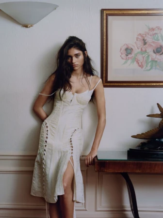 Elegant woman in a white dress posing in an indoor setting, complemented by classic interior decor, natural lighting, and soft color palette.