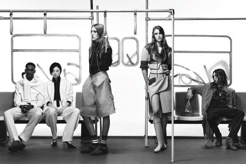Diverse group of models in a subway train, showcasing fashion, black and white photography with creative clothing styles.