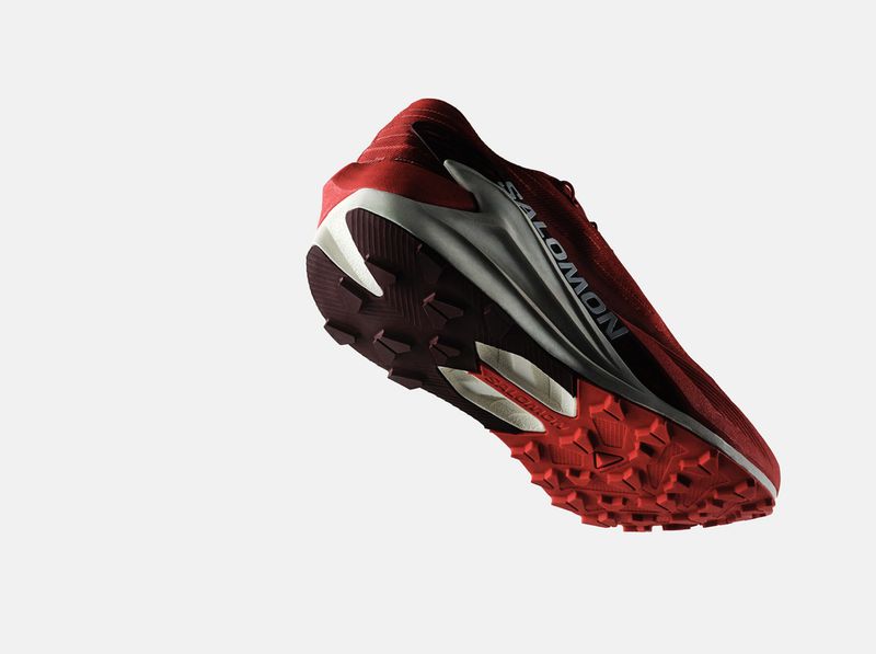 Elevated view of a red Salomon athletic shoe with a white midsole on a white background, showcasing the design and features.