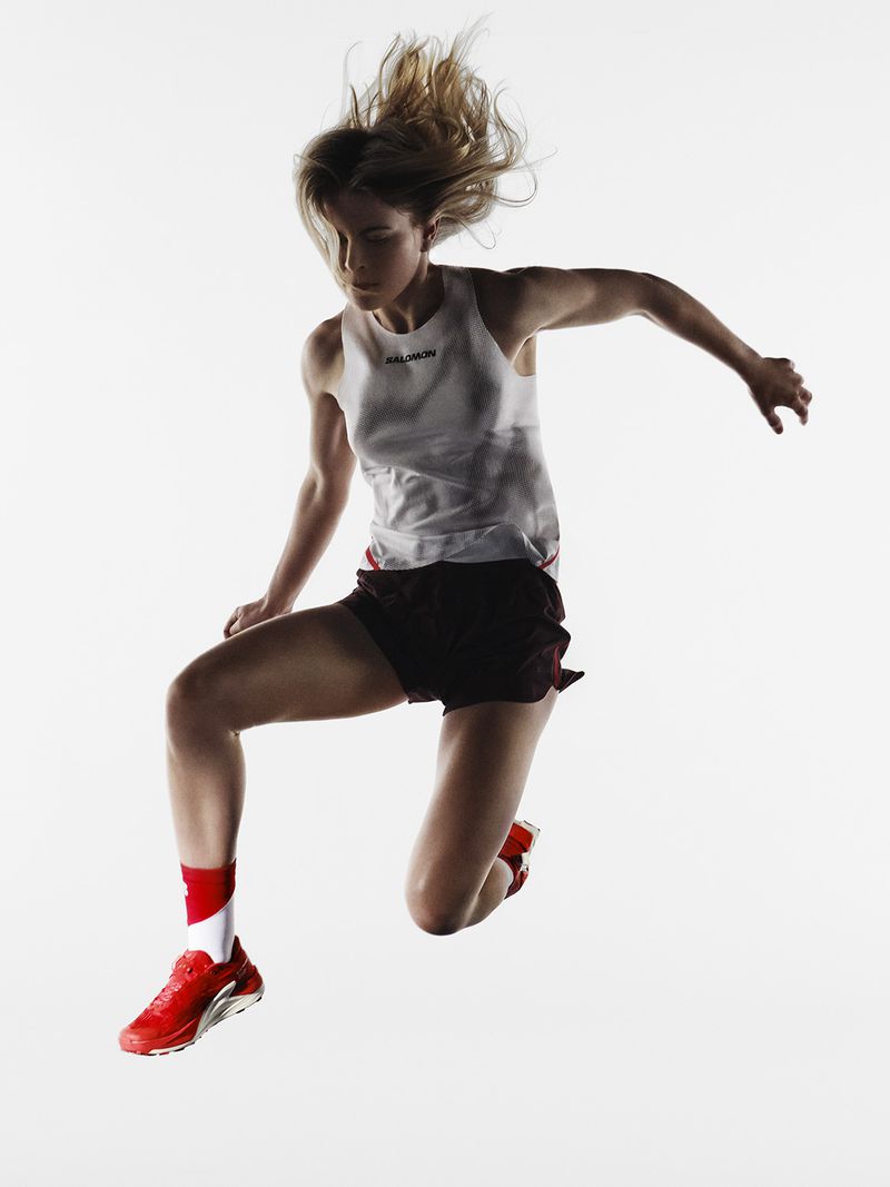 A woman wearing sportswear jumps with energy against a white background, creating a dynamic action shot for sports and fitness themes.