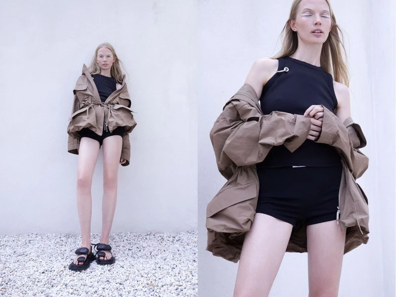 Fashion photo featuring a model in a brown jacket, black top, and shorts, paired with chunky sandals against a plain background.