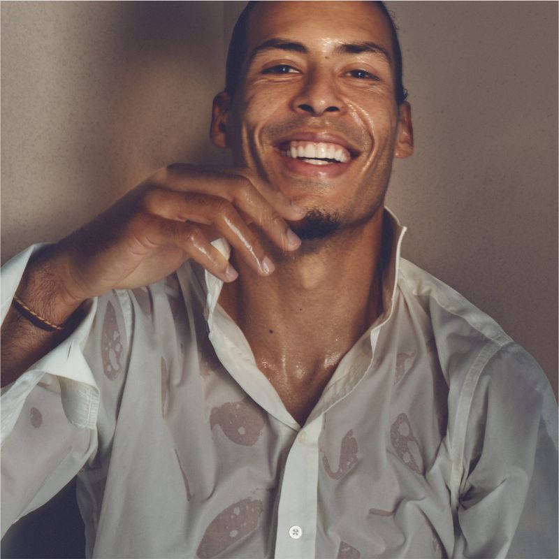 Smiling man with wet hair and white shirt in a close-up shot, showcasing a relaxed and natural portrait with clean, minimalist aesthetic.