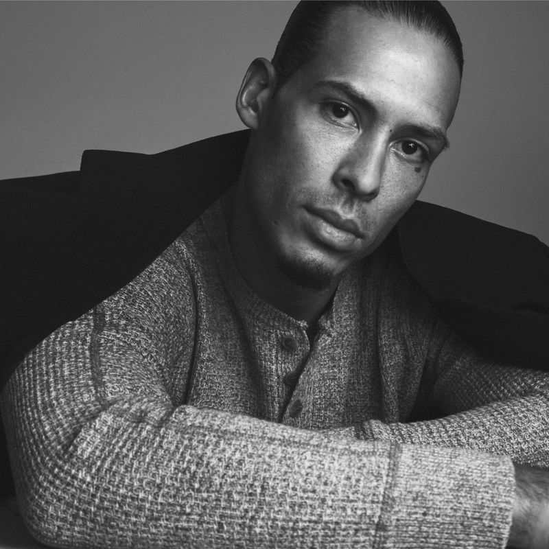 Black and white portrait of Virgil van Dijk wearing a textured thermal henley and draped dark coat for Fantastic Man.