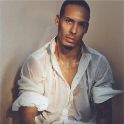 Virgil van Dijk wearing an unbuttoned translucent white collared shirt with rolled-up sleeves in a soft light corner portrait.