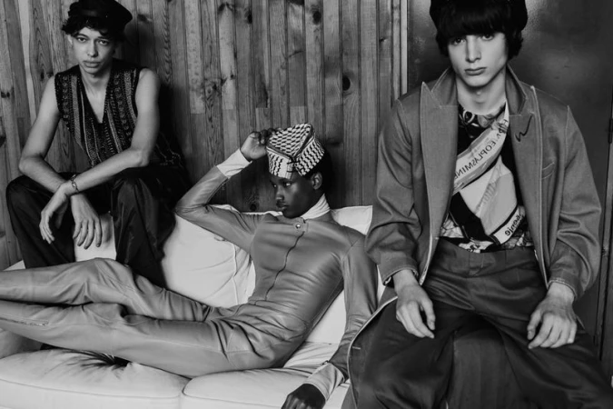 Three young men posing on a white sofa against a wooden wall in black and white fashion photography for Inferno Kids by Fucking Young.