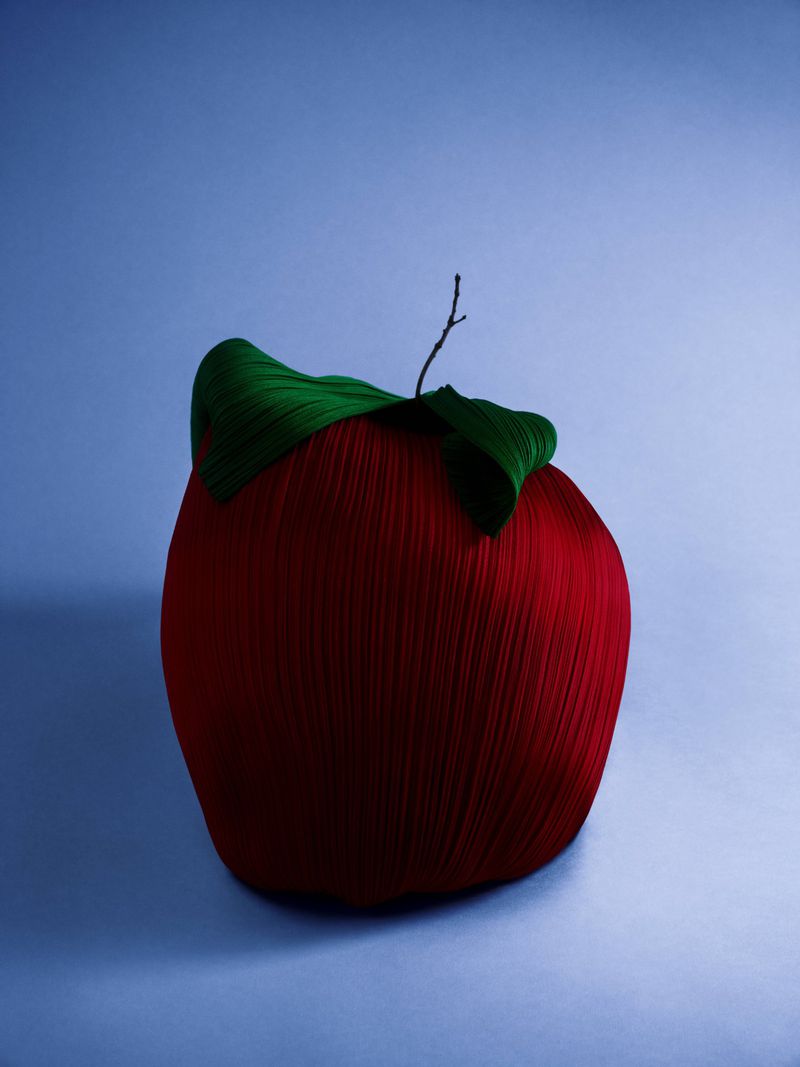 Stylized red apple with green leaves against a gradient blue background, creating a vibrant and modern still life composition.