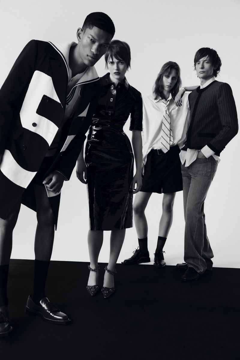 Monochrome fashion editorial featuring four slender models in diverse black and white outfits posing against a stark studio backdrop.
