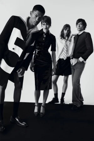 Monochrome fashion editorial featuring four slender models in diverse black and white outfits posing against a stark studio backdrop.