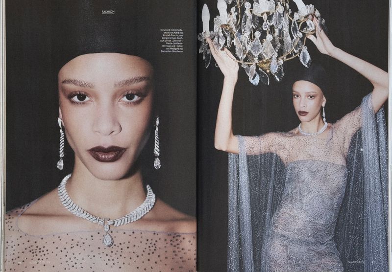 Fashion editorial featuring a woman in a sheer, sparkly dress with jewelry, posing next to a chandelier, with a dark backdrop.