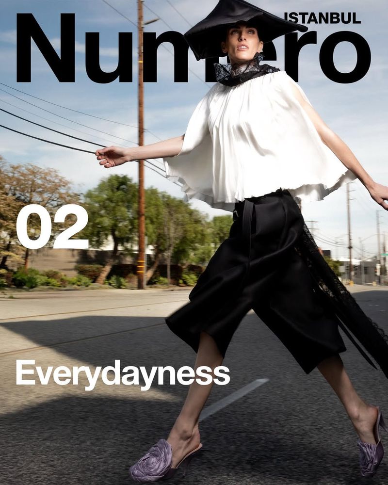 Fashion editorial cover featuring a model in black and white, walking on a street for Numero Istanbul, with a clear sky background.