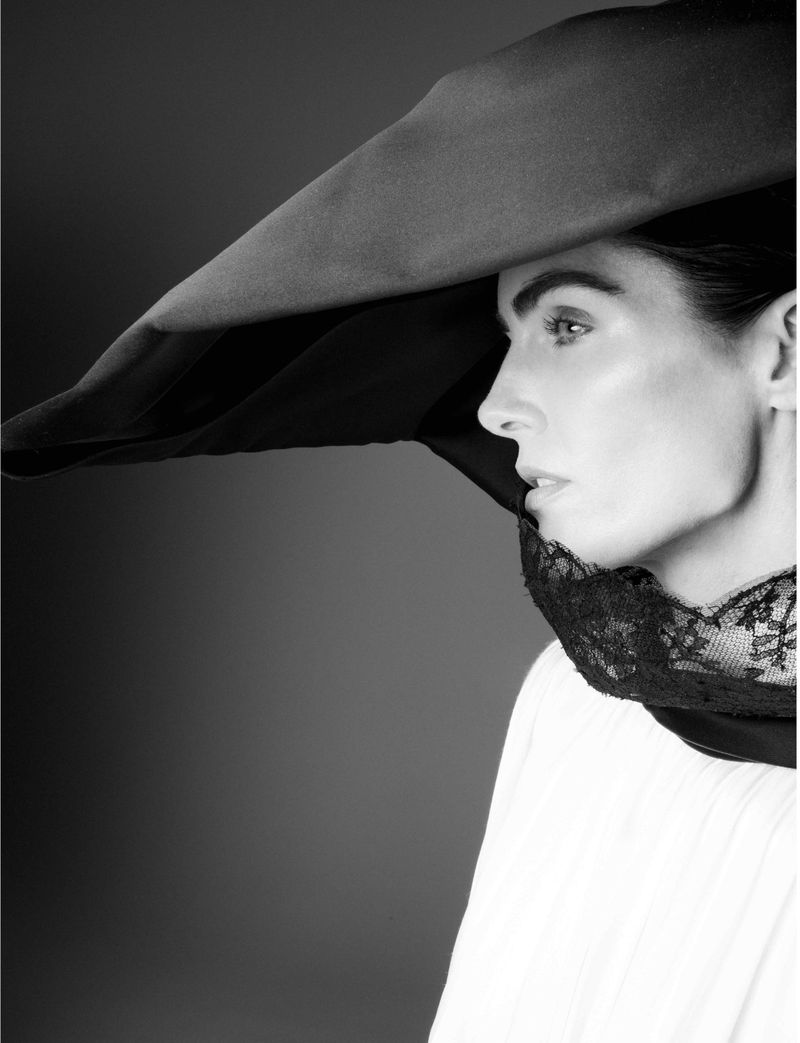 Striking monochrome portrait of a woman in a wide-brimmed hat, showcasing a profile view with intricate lace detailing, captured in a studio setting.