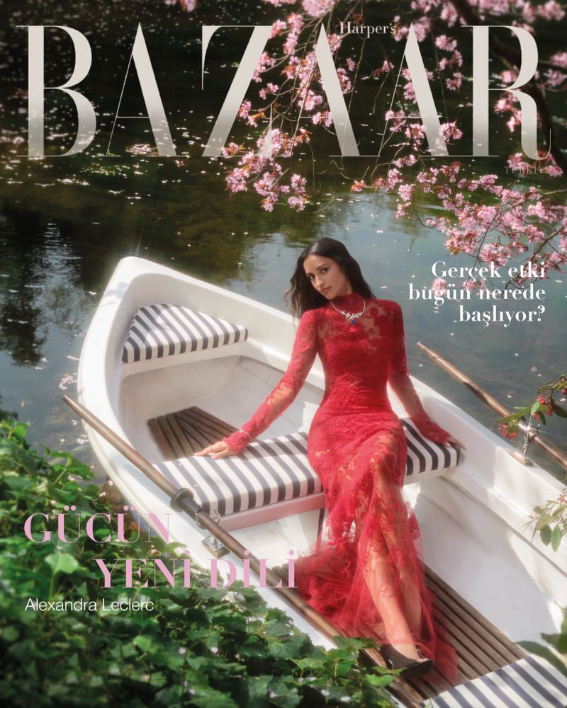 Magazine cover featuring a woman in a red lace dress sitting in a boat on a lake surrounded by cherry blossoms, with the 'BAZAAR' logo.