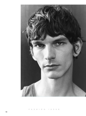 Black and white portrait of a young adult man with short wavy dark hair, fair skin, wearing a tank top, and facing the camera.