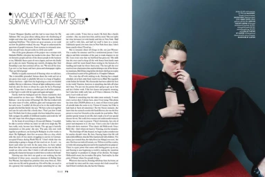 Actress Elle Fanning wearing a black suit reclining on a red sofa across an editorial magazine spread.