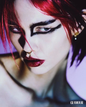 Close-up beauty portrait of model Lola Gleich with bold black graphic eyeliner, vibrant red hair, dark glossy lips, and a septum piercing.