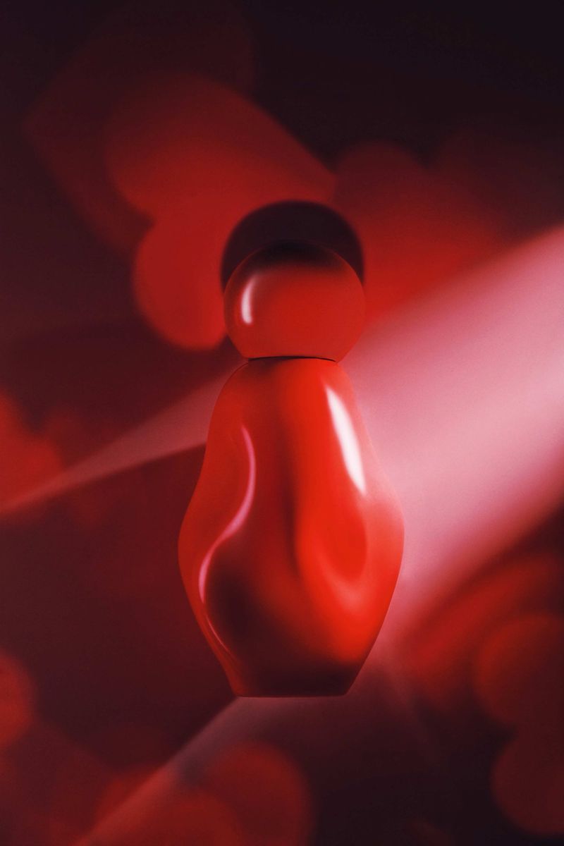 Elegant red perfume bottle on dark background with bokeh and light rays, conveying luxury and sophistication in a studio shot.