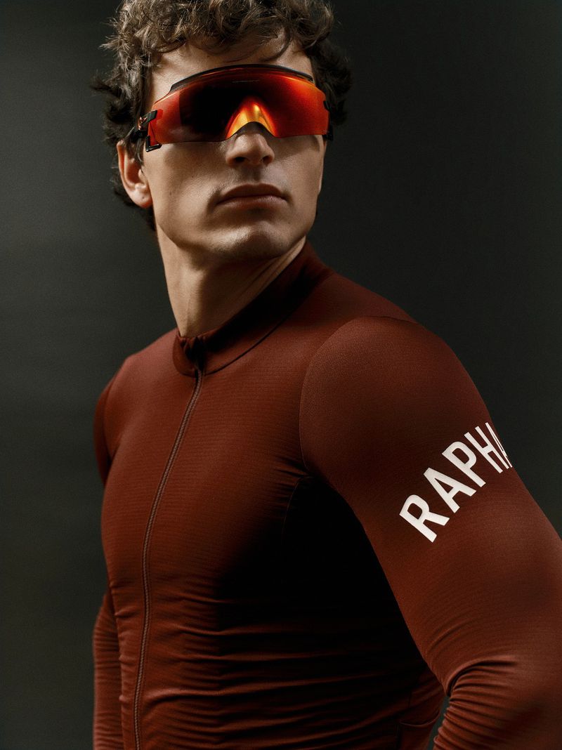 Man in cycling jersey and sunglasses. Close-up studio shot highlighting sportswear and athletic fashion against a dark background.