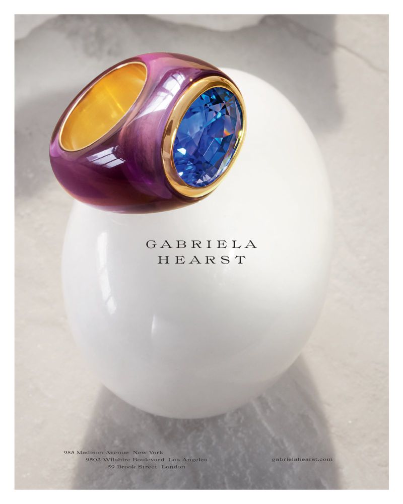Close-up of a ring with a large blue gemstone, set against a white sphere, showcasing the piece's design and texture in a studio shot.