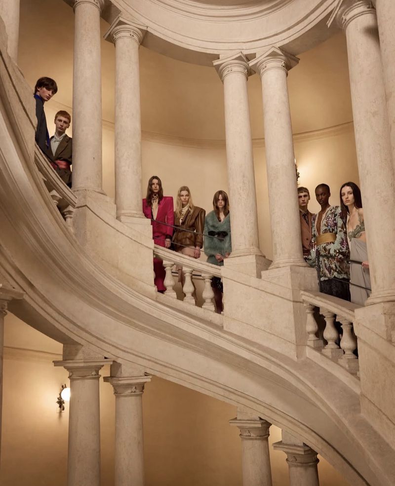Fashion shoot on a marble staircase. A group of young male and female fashion models pose in bright vintage-inspired outfits for a fashion editorial.