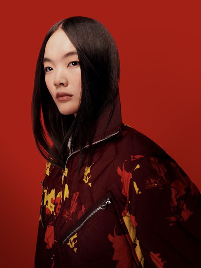 Portrait of an Asian woman wearing a floral patterned jacket against a solid red background, studio lighting, and sleek dark hair.