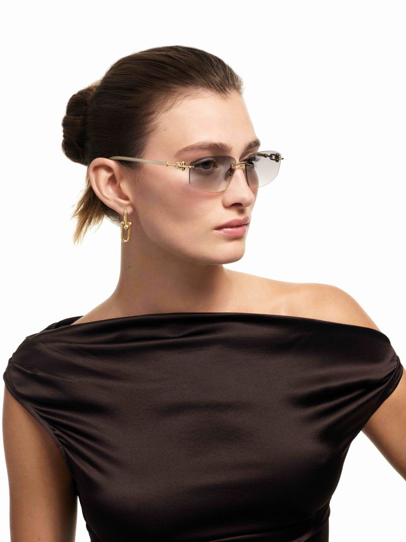 A woman poses in a brown dress and eyeglasses in a close-up studio shot. Fashion and beauty concept with white background.