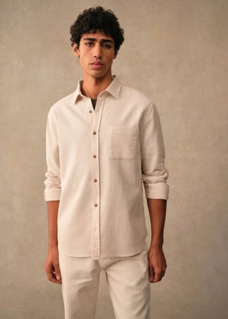 Maxime El Hanafi wearing a cream button-down shirt and matching trousers in a studio shoot for Octobre Editions.