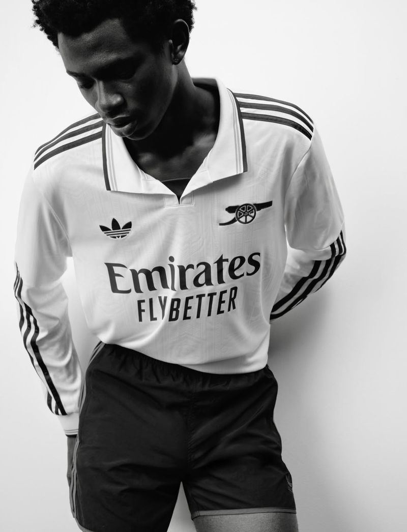 Monochrome portrait of a young adult male in a long-sleeve athletic shirt and shorts against a white background in a studio setting.