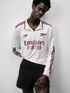 Model Willie Fidelis posing in a long-sleeve white and burgundy Adidas Arsenal kit jersey with black athletic shorts.