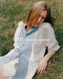 Model lying on green grass wearing a striped short-sleeve button-down shirt for Ami