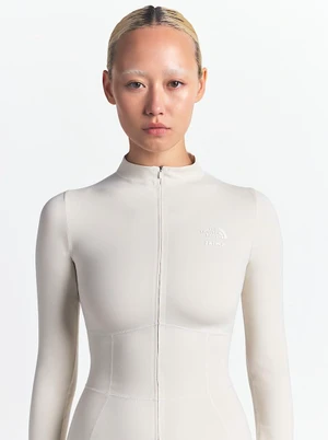 Model wearing a light cream zip-up mock-neck top against a clean white background
