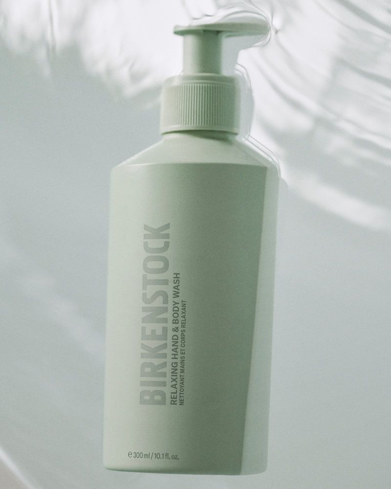 Birkenstock hand and body wash in a light green bottle with pump dispenser, set against a soft, bright backdrop.