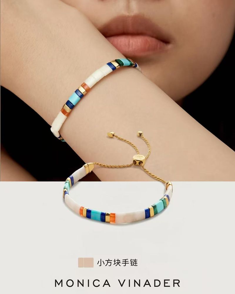 Woman's wrist with Monica Vinader bracelet, featuring white, turquoise, and gold tile elements, paired with a second bracelet.