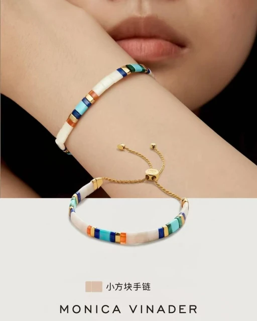 Woman's wrist with Monica Vinader bracelet, featuring white, turquoise, and gold tile elements, paired with a second bracelet.