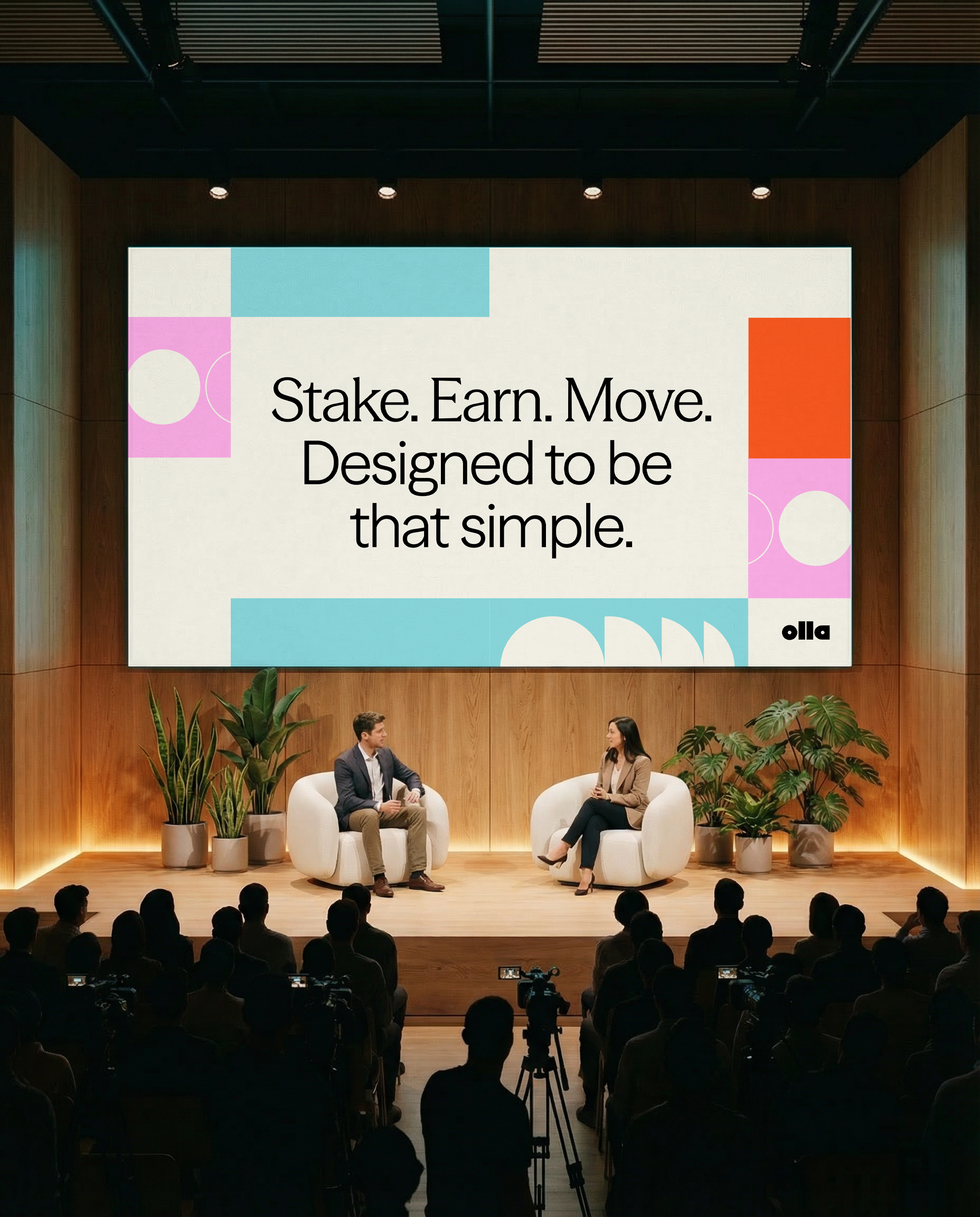 Two speakers seated on a wooden stage in white armchairs beneath a large screen presenting Olla brand identity to an audience.