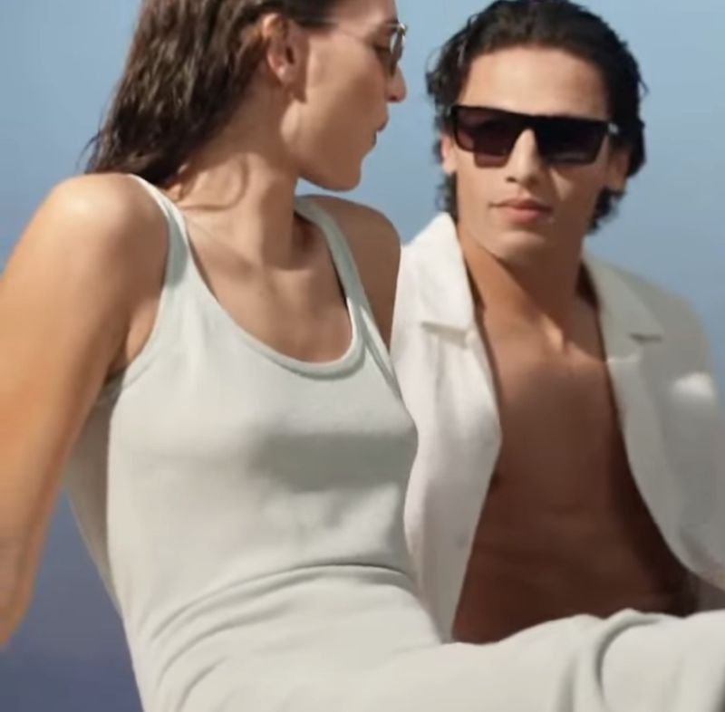 Man and woman wearing sunglasses outdoors in white summer attire for Calvin Klein Eyewear
