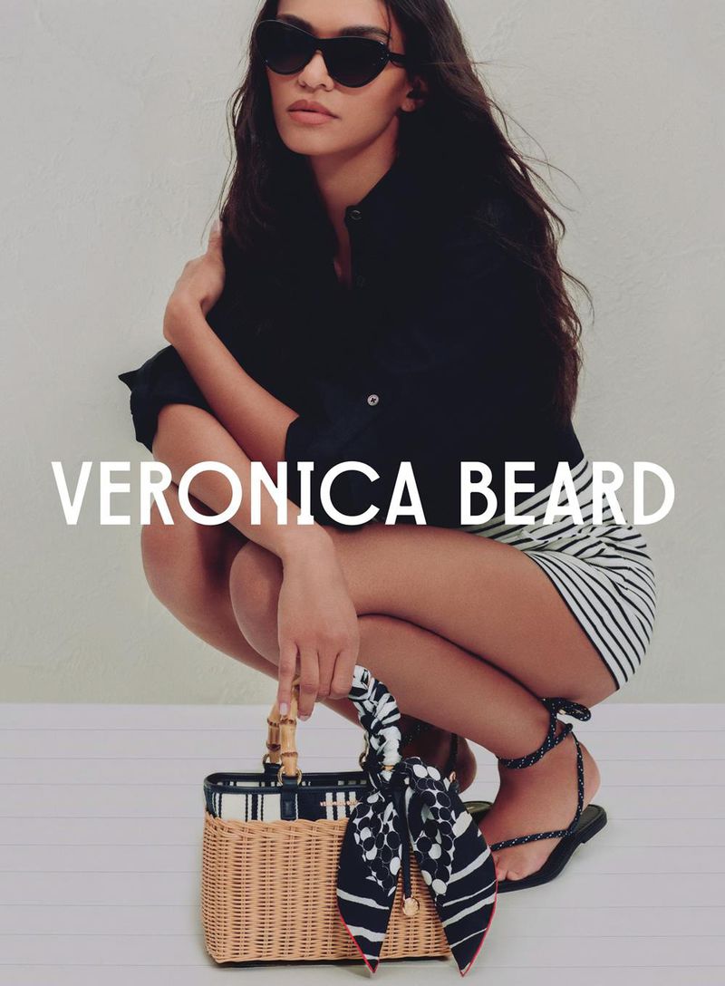 Woman in black top and striped shorts squats with a basket and scarf, posing in a fashion editorial for Veronica Beard.